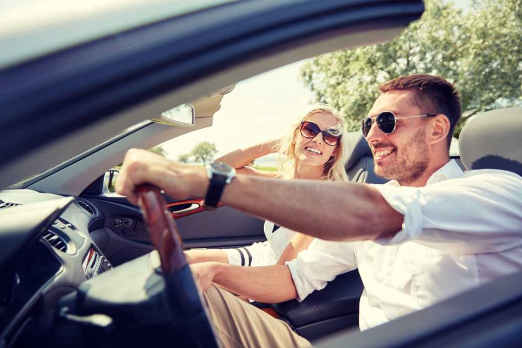 Man and woman wearing sunglasses in a convertible