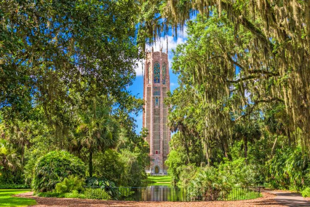 stone tower with stained glass windows rising amid trees and plants