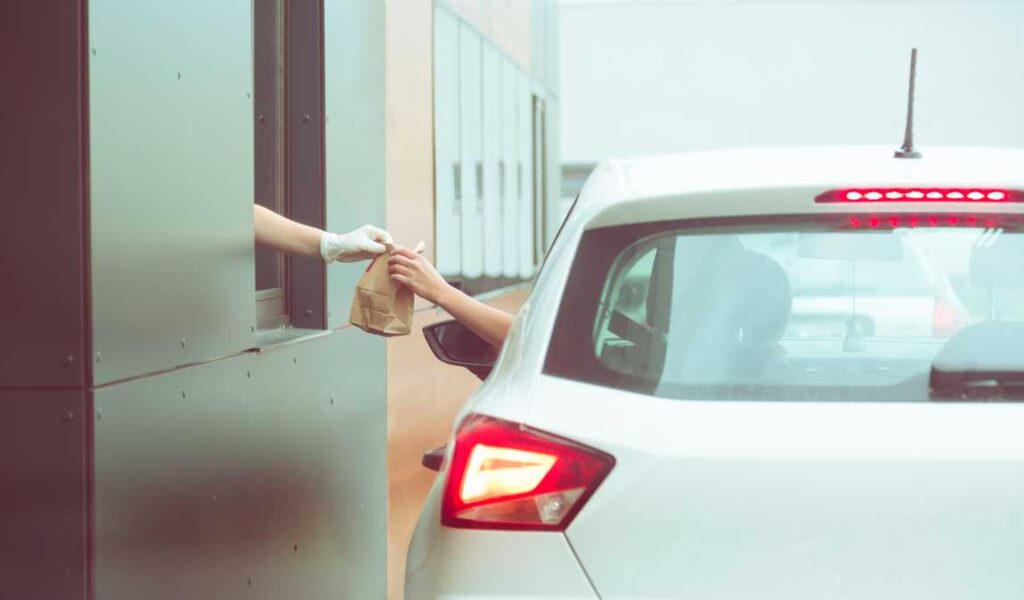 White car getting fast food bag at the drive through