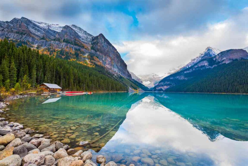 Clear blue waters of Lake Louise with a cabin, surrounded by mountains