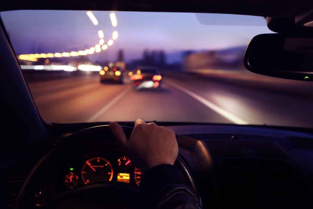 Person behind the wheel driving at night.