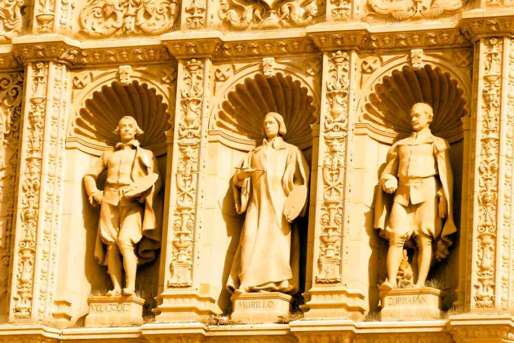 Statues carved from tan stone into the side of a building