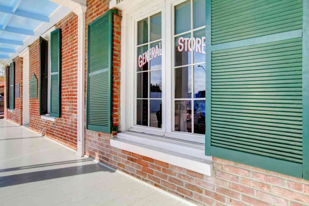 Brick house with green shutters and the words general store on the window