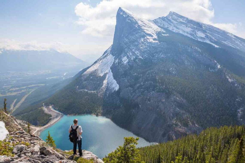 Man standing on cliff over mountain lake 