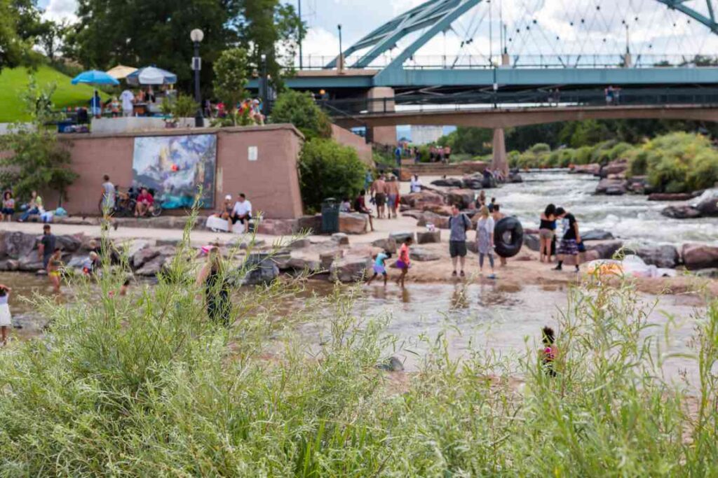 people cooling off in the river below a bridge