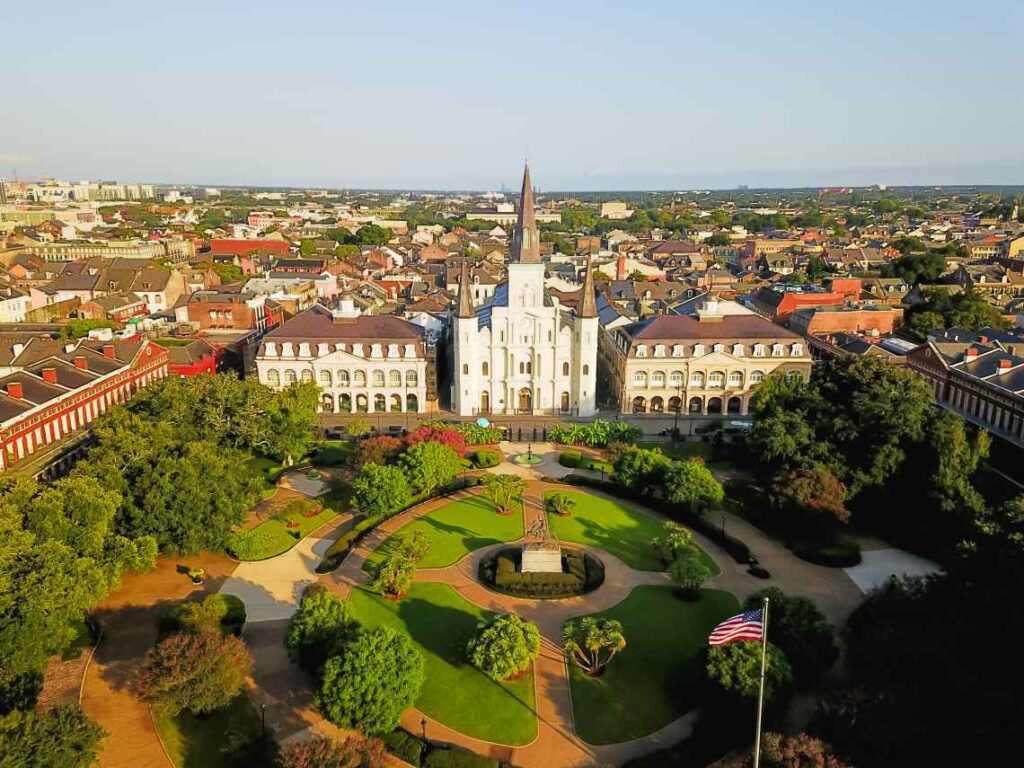 green city square with large white cathedral in the background