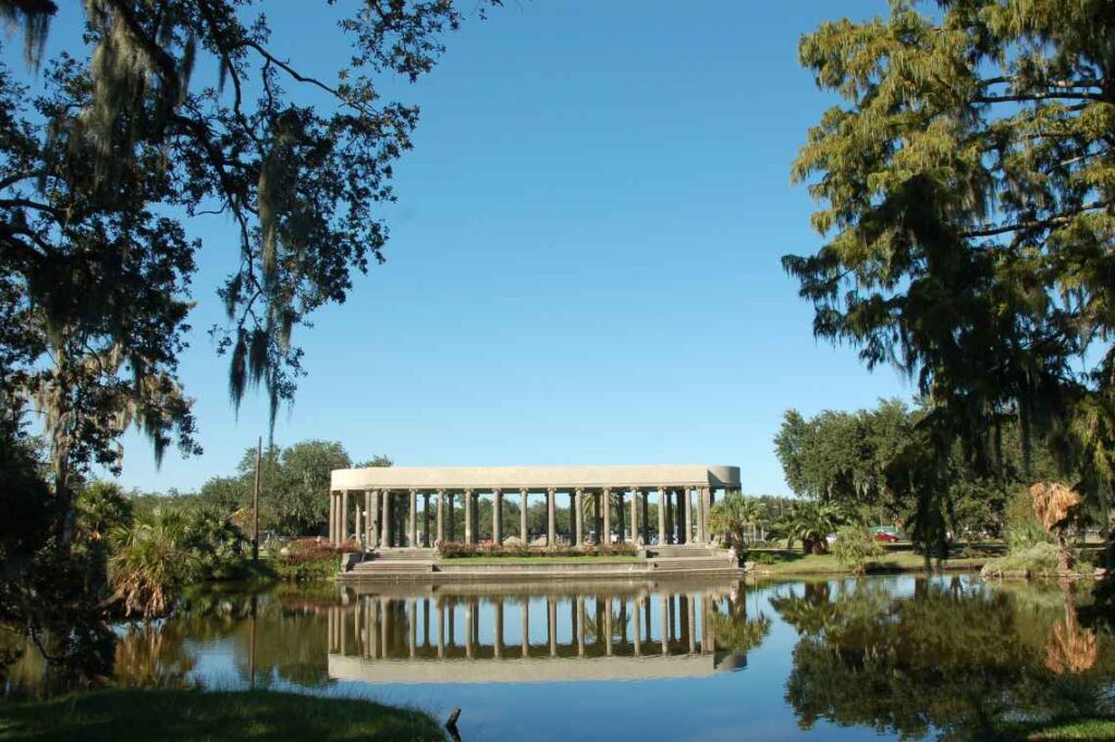 structure with columns sitting on a lake surrounded by trees