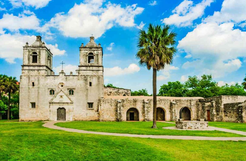 Historic spanish-style church with palm trees and blue skies