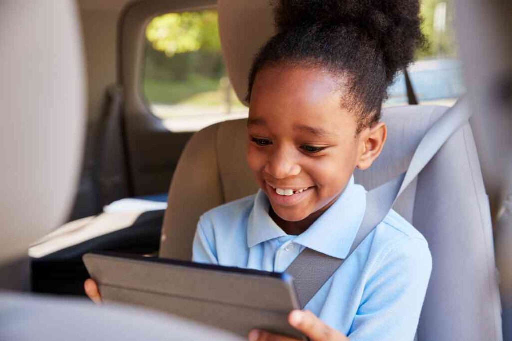 girl smiling at tablet in a car