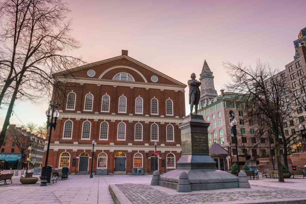 historic faneuil hall at sunset with a plaza and statue in front of it