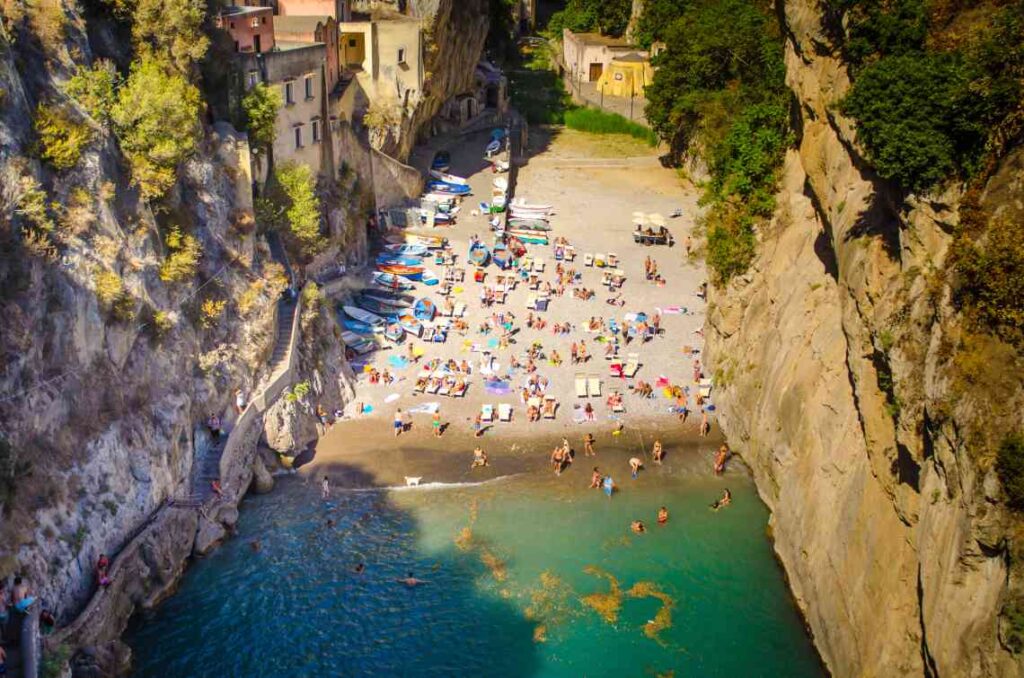 small beach in between rock walls with blue green water