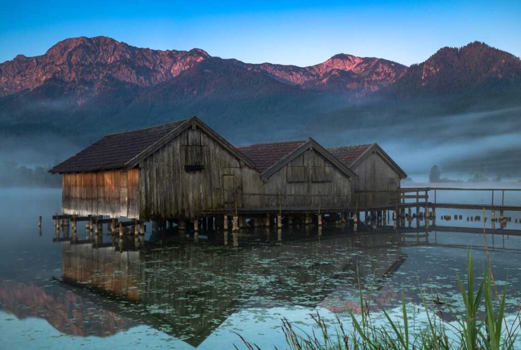 boathouses on a lake in the fog with mountains in the background