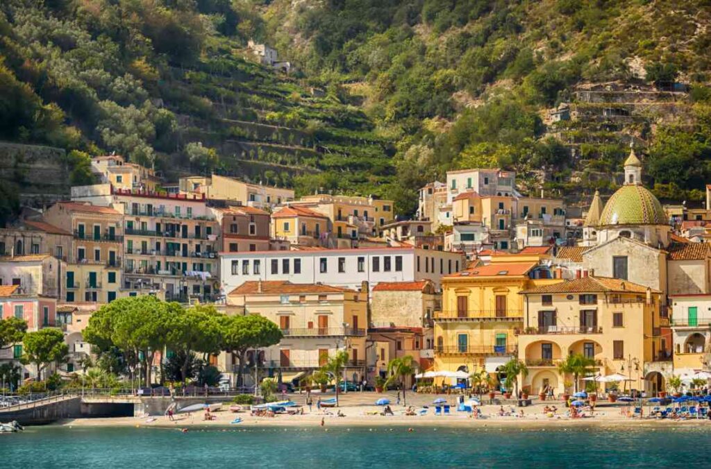 a beach with bright colorful buildings rising up a hillside from blue ocean