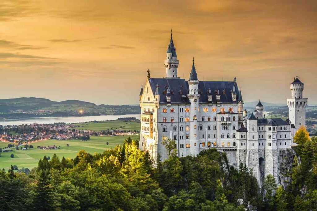 fairytale castle neuschwanstein on a hill overlooking a town and lake