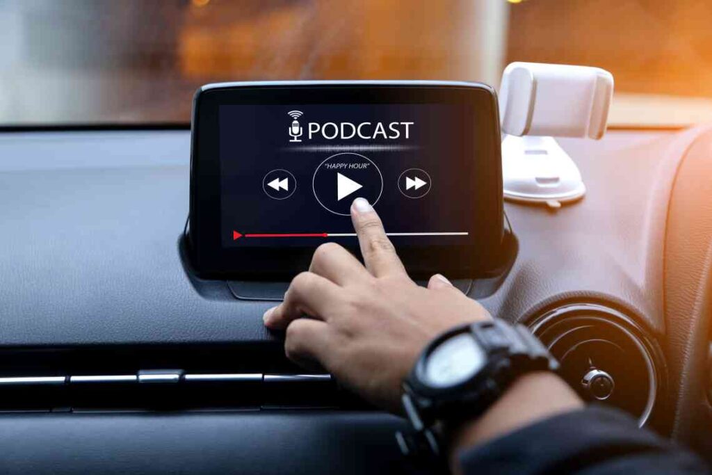 person touching car touchscreen with podcast playing