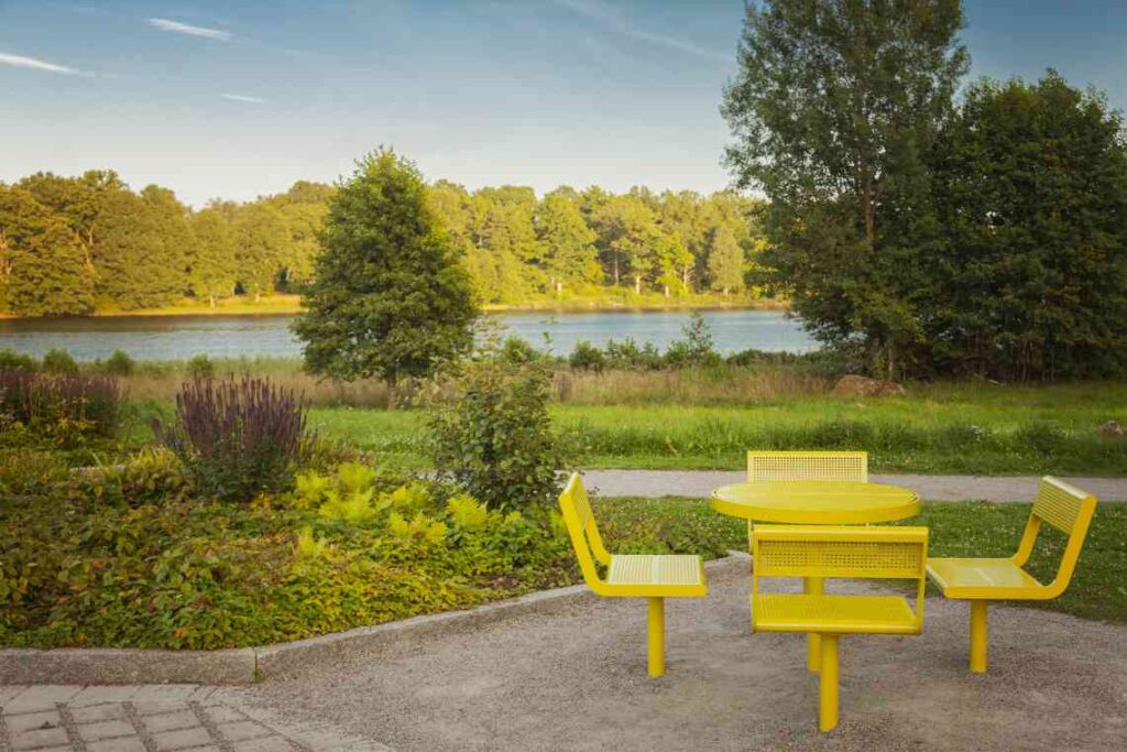 yellow table and four chairs next to a lake at a rest stop