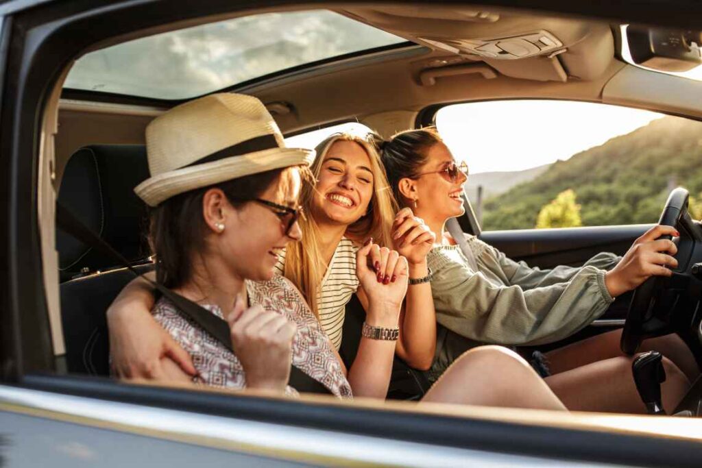 three women having fun and laughing in a car