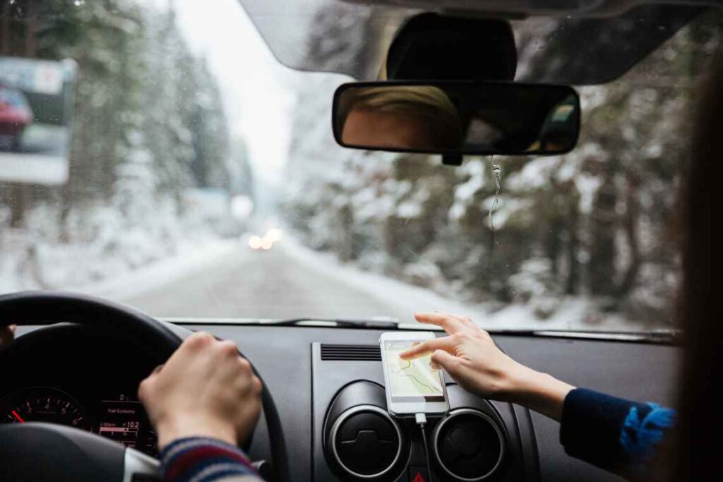 couple in car with woman swiping on smartphone map on dashboard