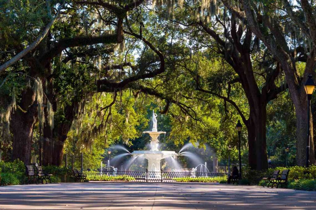 white fountain in a park and trees hung with spanish moss
