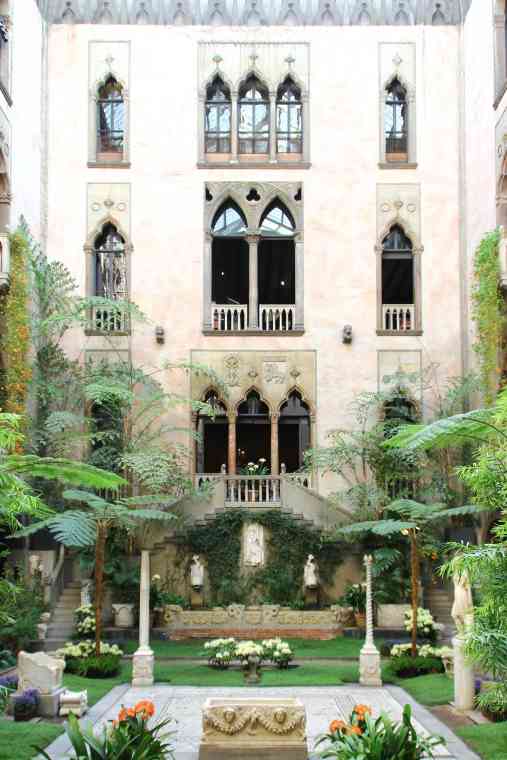 museum building with courtyard with flowers and palm treees