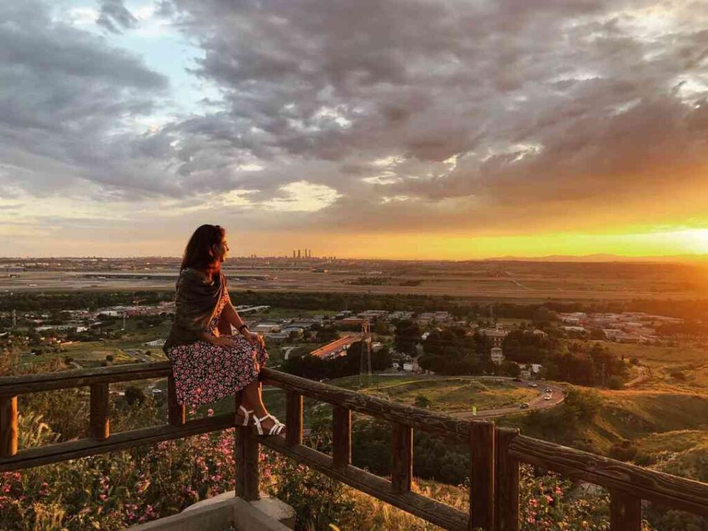 woman in a dress at viewpoint overlooking a town at sunset