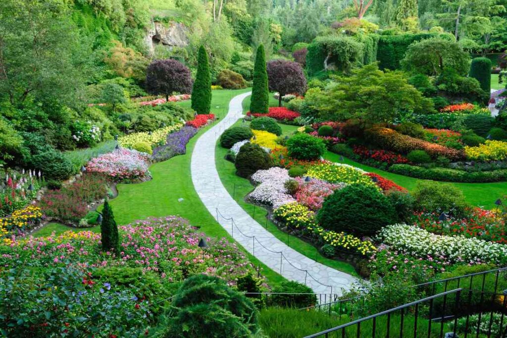 landscaped grass flowers and bushes with gray stone pathway