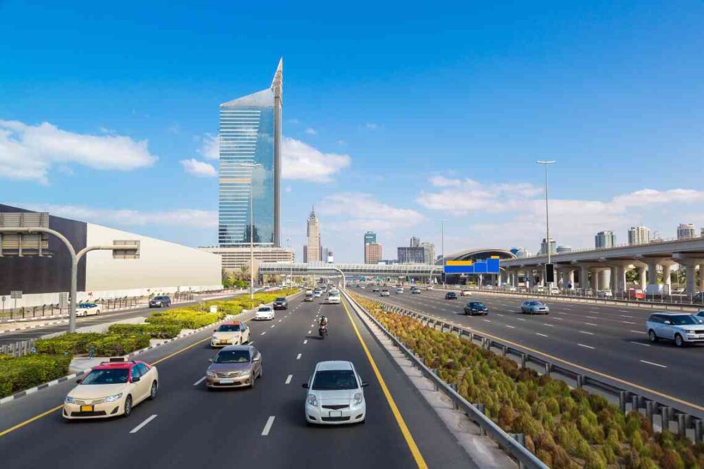 cars on multilane freeway with skyscrapers in the background in dubai