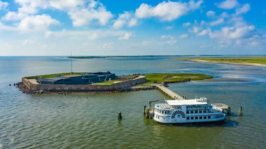 white two level ferry boat docked at small island with fort sumter