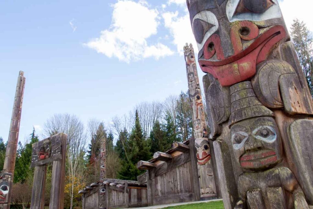 weathered wooden totem poles outside with trees in the background