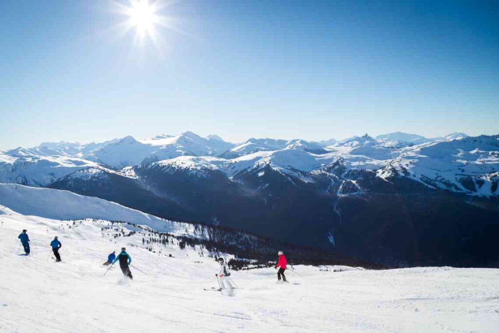 downhill skiers at blackcomb resort with snow-covered mountains in the background