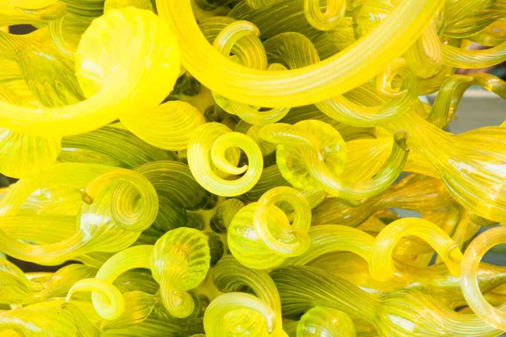 close shot of yellow glass sculpture with curls coming out of the center