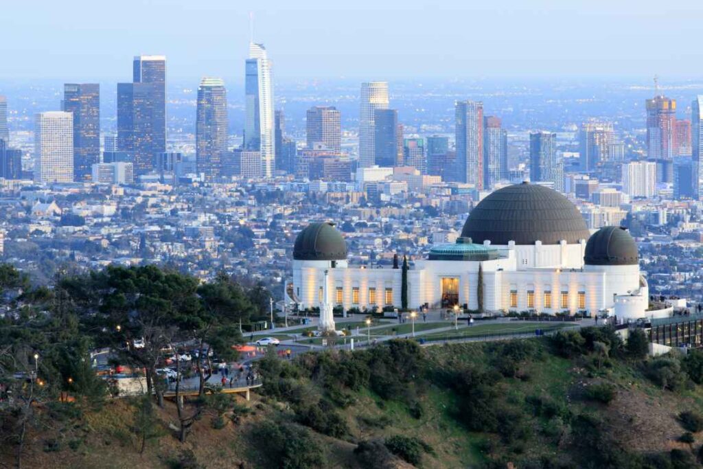 Up close shot of white Griffith Observatory with black domes, overlooking downtown LA