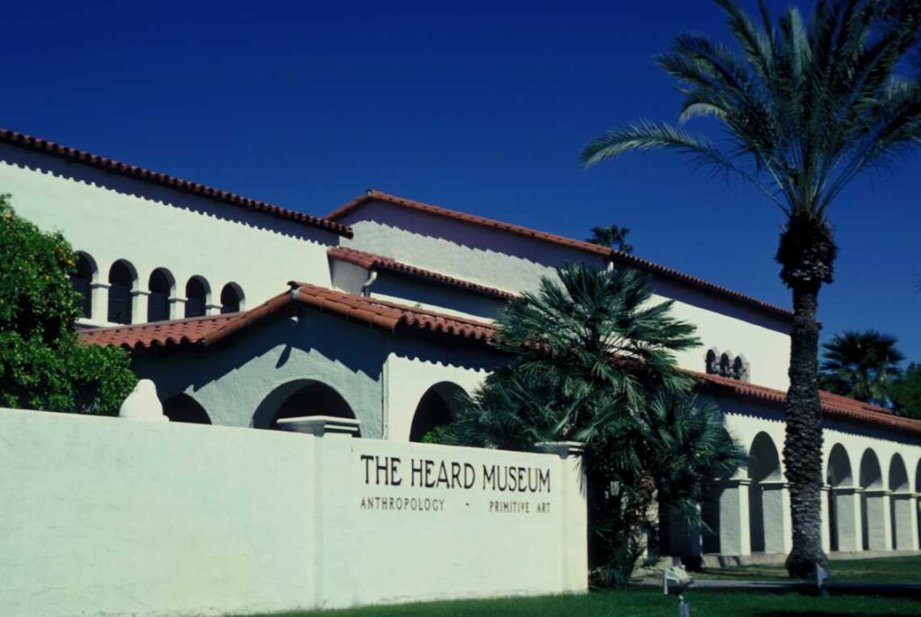 white spanish style heard museum with red roof and palm trees in front