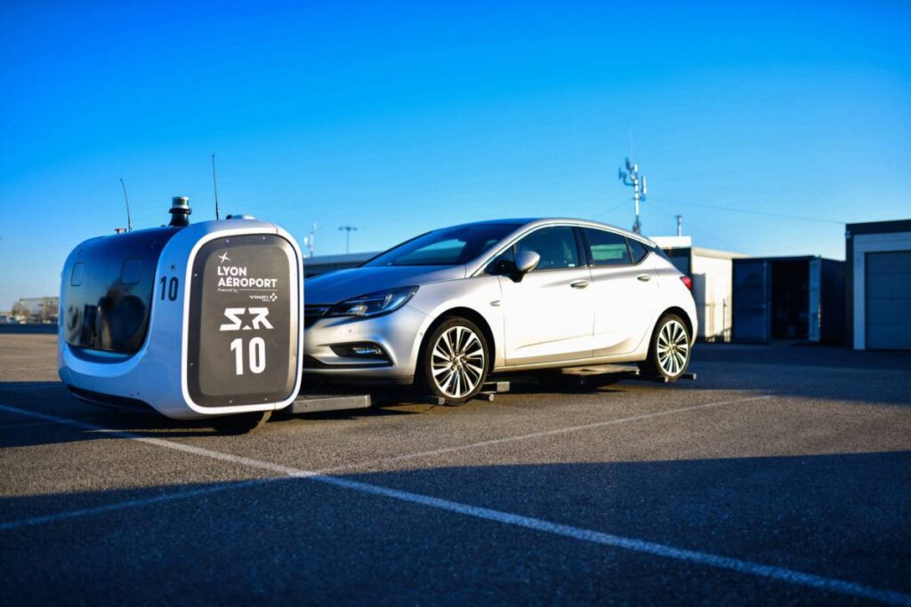 silver 4 door hatchback car with autonomous robot in a parking lot