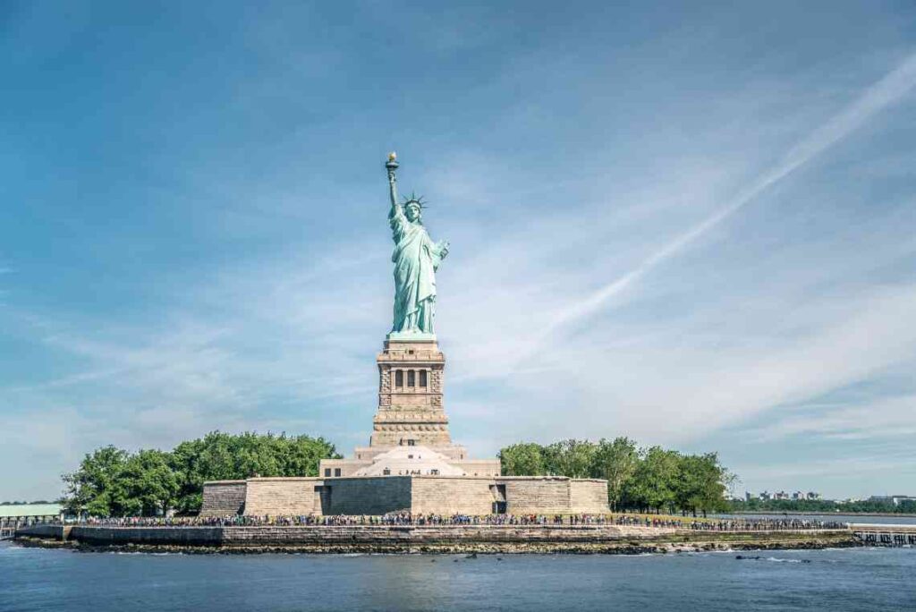 close up of the statue of liberty from new york harbor with people at the base in front of a blue sky