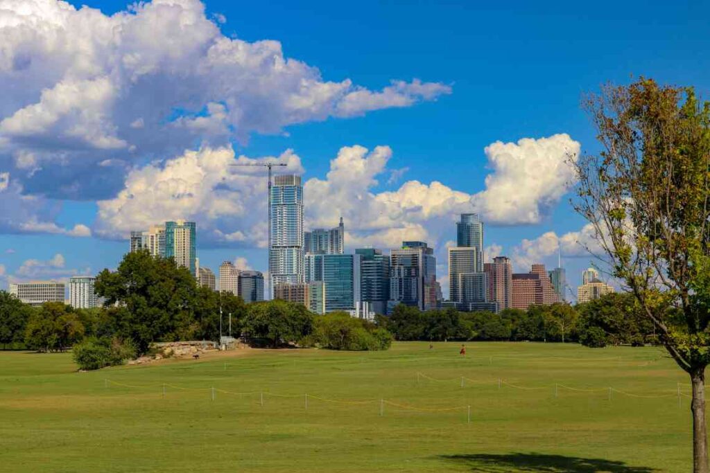large green lawn of zilker park with austin skyline in the background