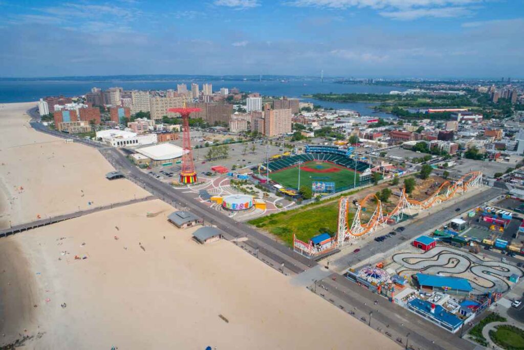 Utsikt från ovan över Coney Island med en stor badstrand till vänster och nöjesparken till höger