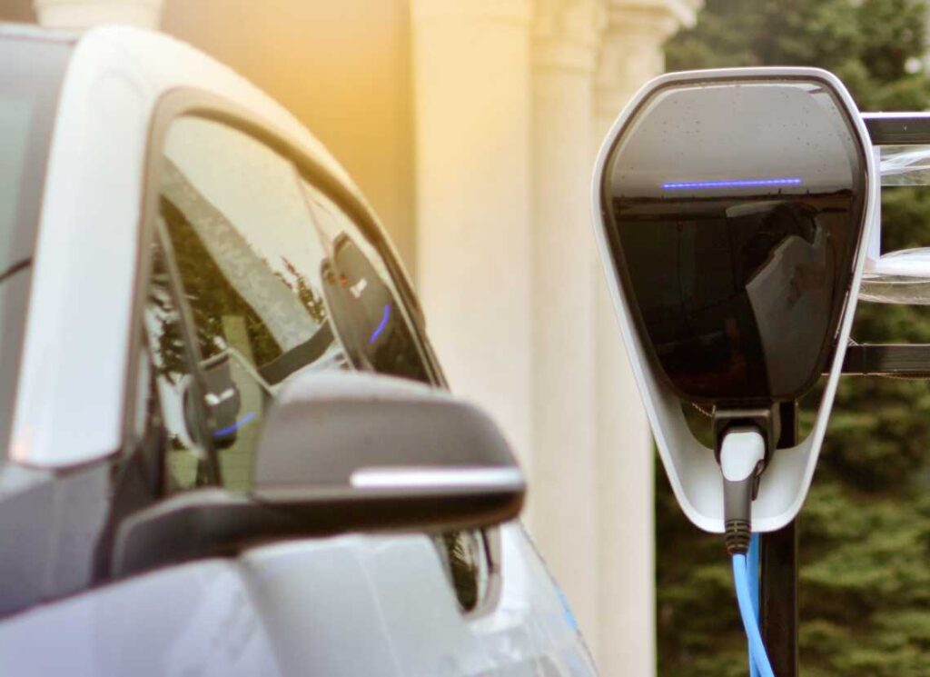 close up of electric vehicle plugged into shiny black charger with horizontal blue light