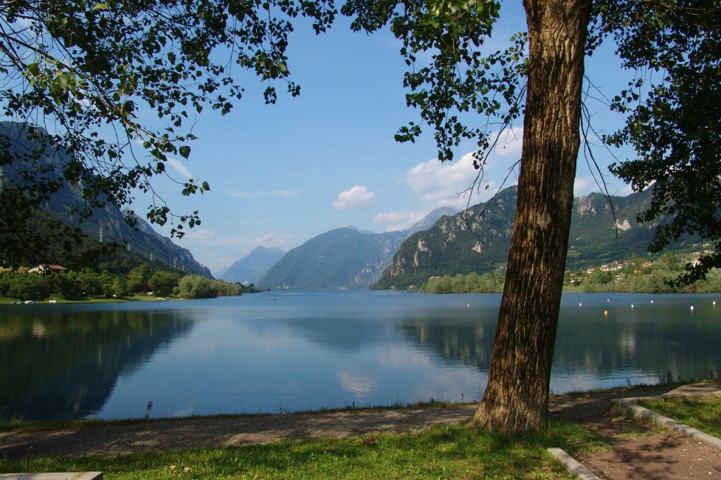 placid lake d'idro surrounded by mountains and green trees