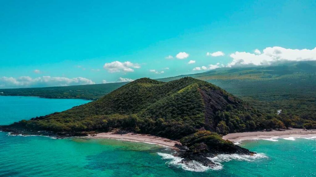 Overhead view of beach at Makena State Park with green mountains and clear turquoise water