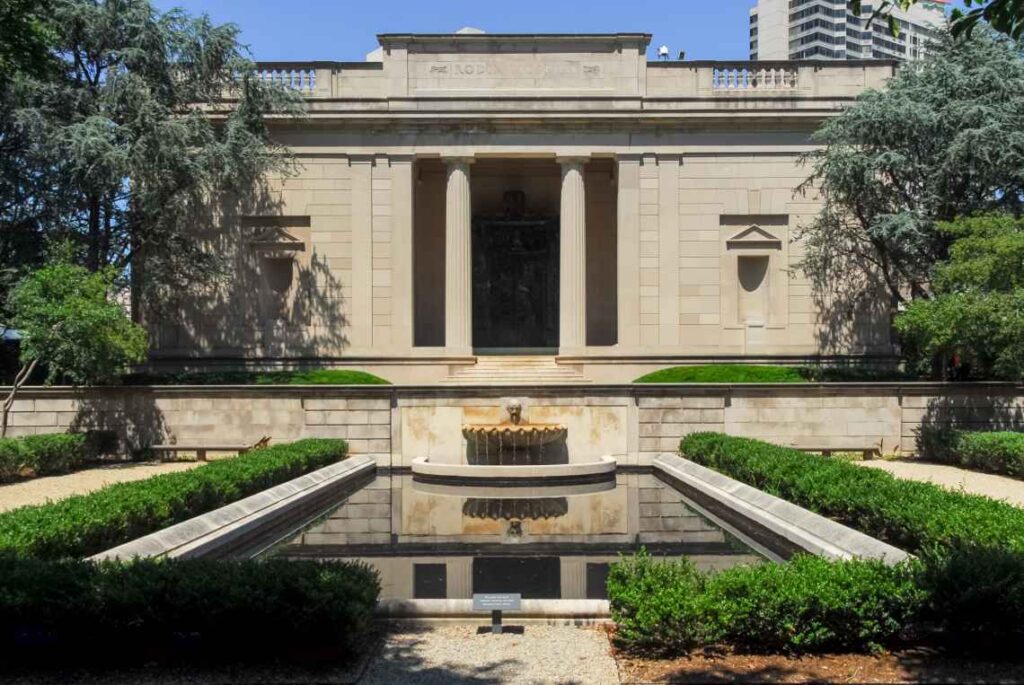 light brown outside of the rodin museum in philadelphia with a reflecting pool and trees