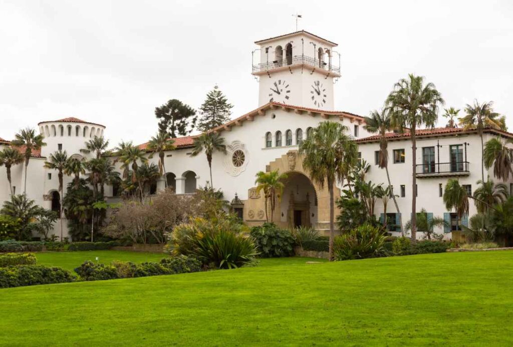 spanish style white santa barbara county courthouse with palm trees and green grass