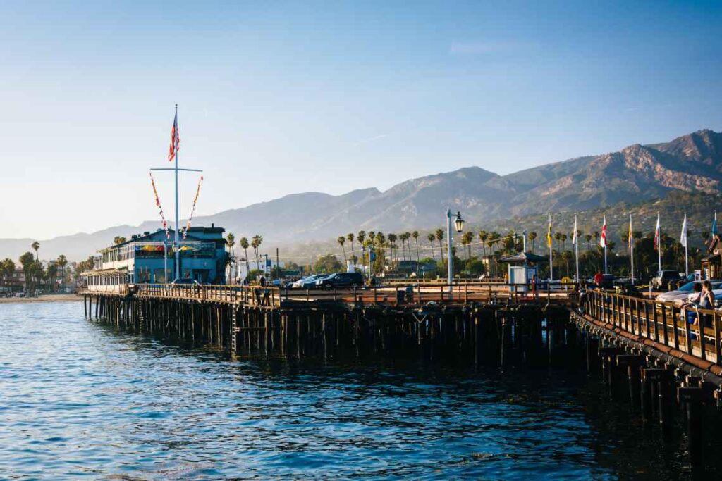 long wooden wharf along the water with mountains in the background