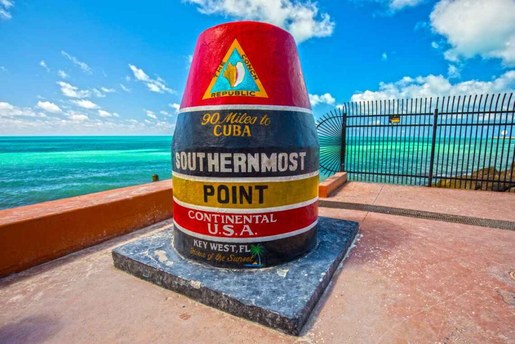 red, dark blue and yellow marker for the southernmost point in the continental usa, with turquoise water behind it