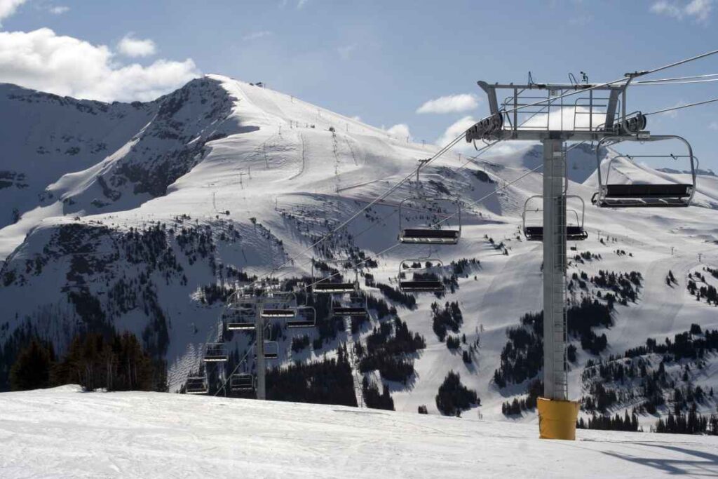 open ski lift above snow with snow covered mountains behind