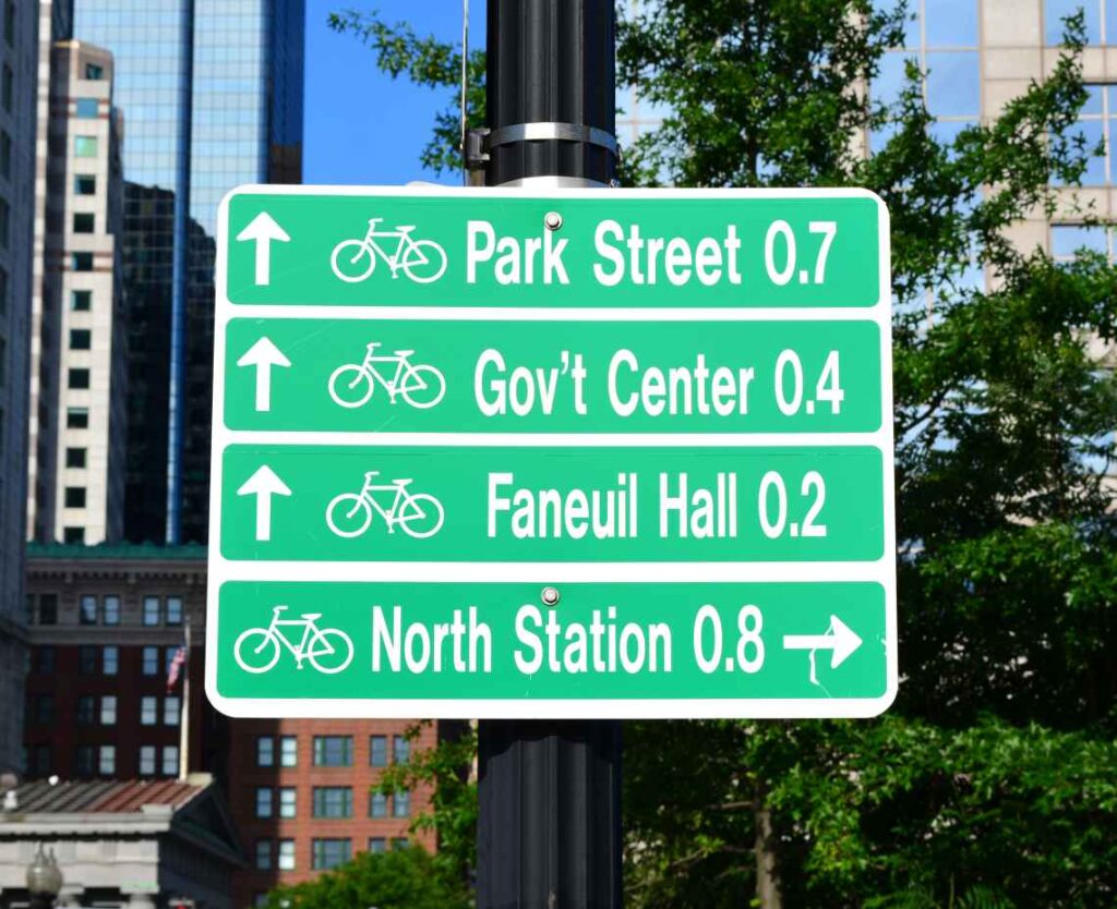 green and white sign with directions and distances to destinations in boston