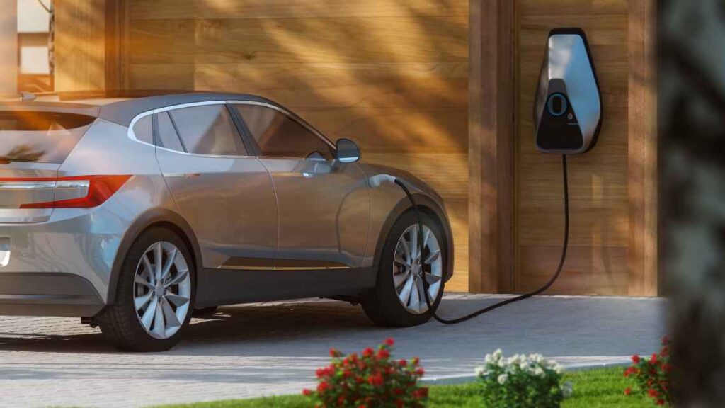 small tan electric SUV plugged into a home electric vehicle charger parked on a driveway