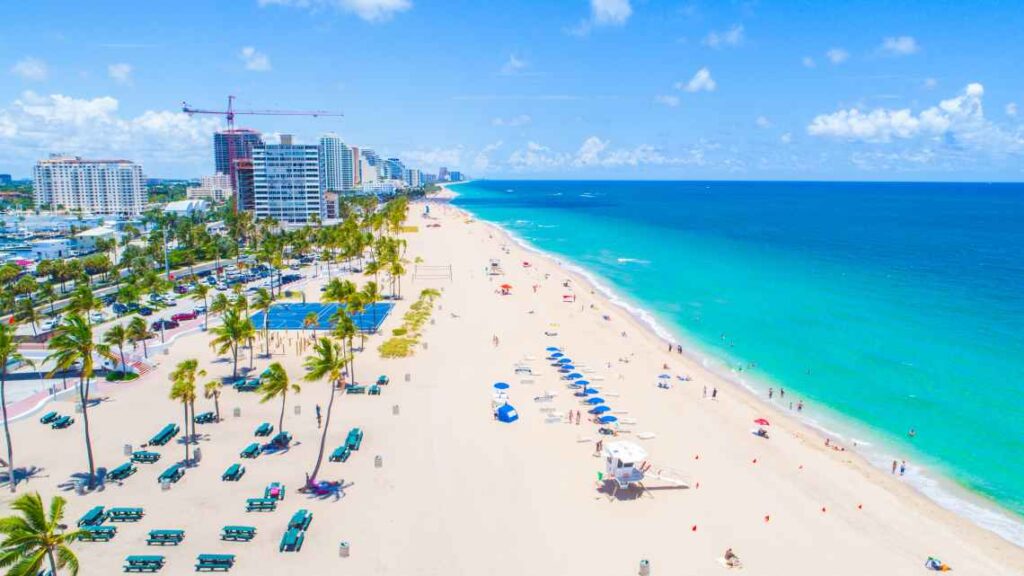 wide white sand fort lauderdale beach with blue umbrellas and blue-green water