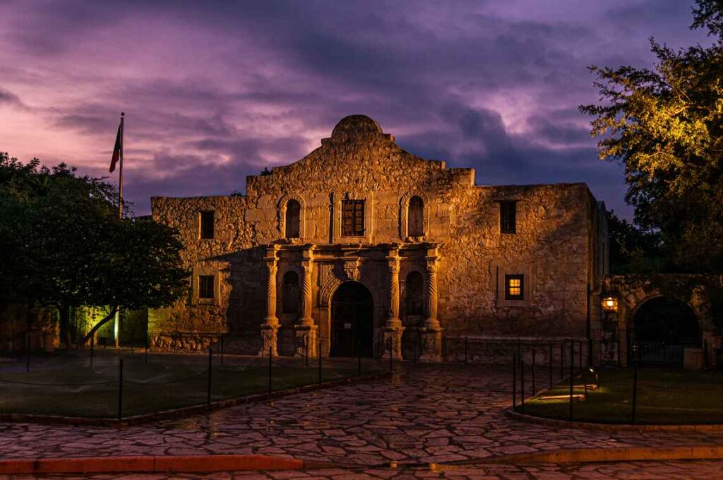 frente de pedra do alamo à noite iluminada com um céu roxo acima