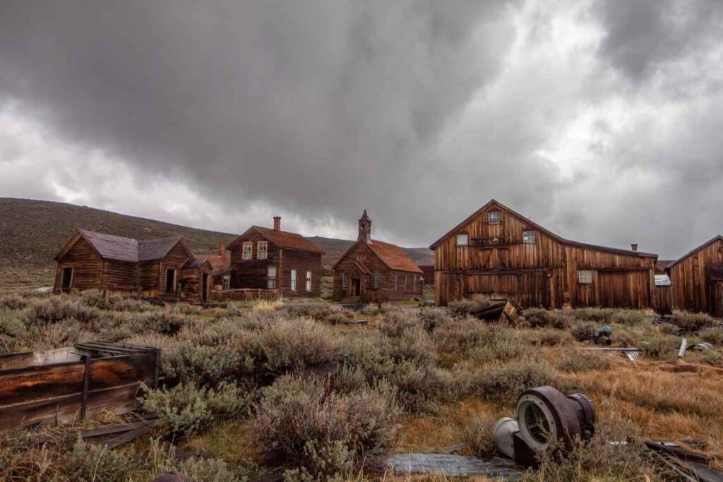 preserved but abandoned wooden buildings of Bodie california under a gray sky with lots of clouds